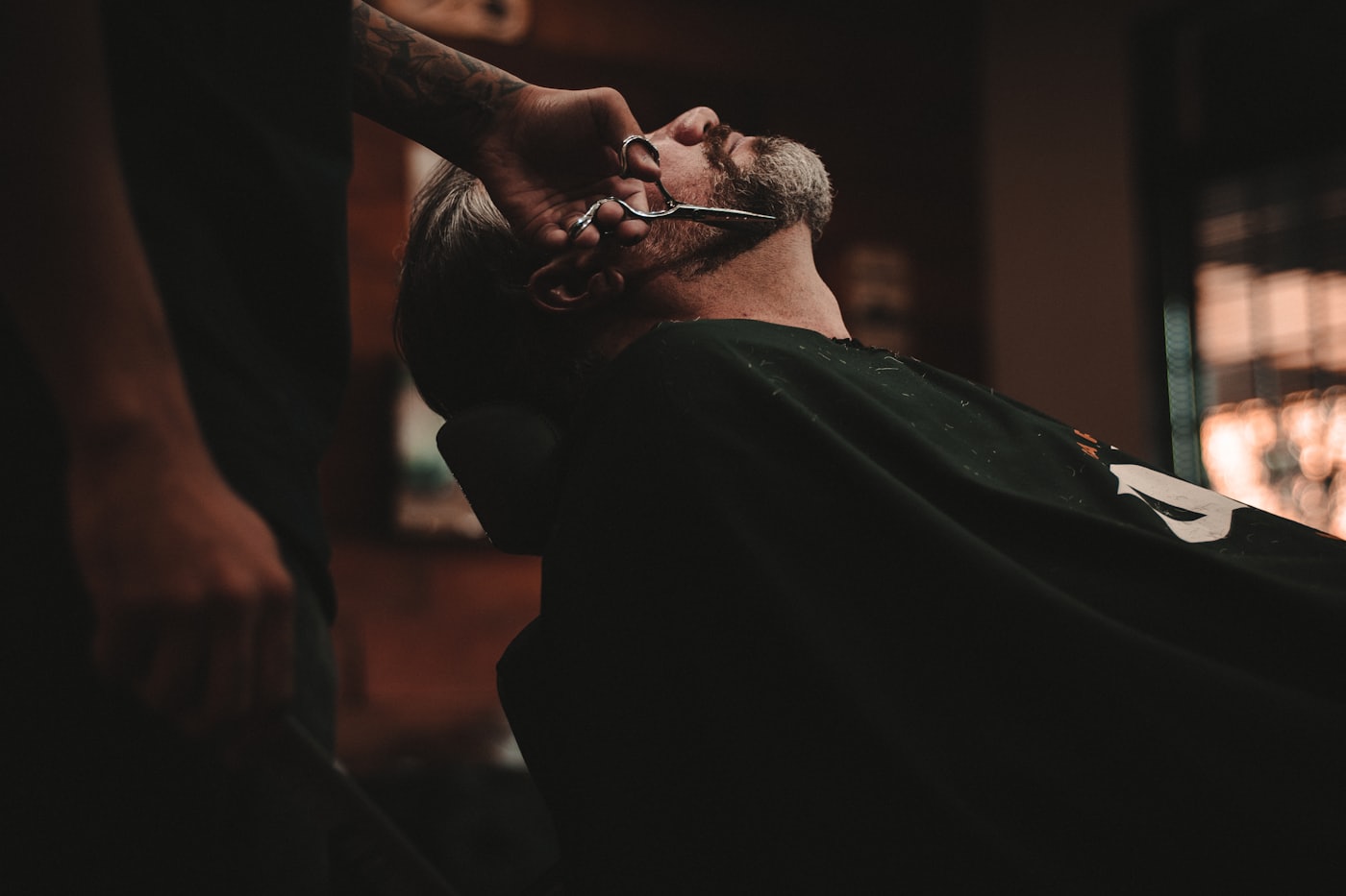 Barber trimming a client's beard at Gentleman Barbershop